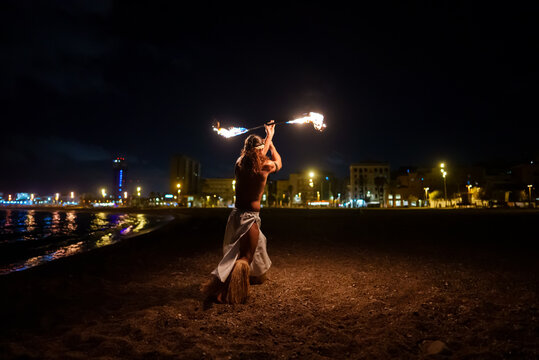 man holds burning fire batons in his hands