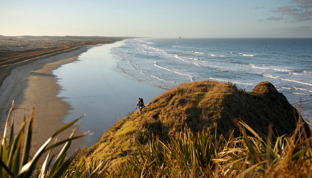 A male hiker looks down the long beach ahead. 