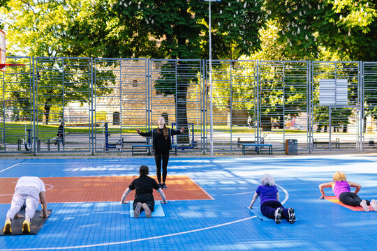 Trainer showing to adult people process of exercises