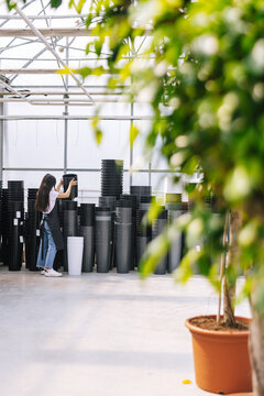 Female florist sorting assortment of vases in shop