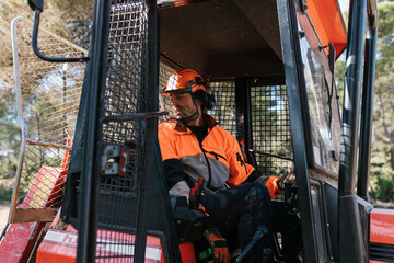 Male worker driving tractor in forest