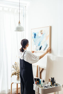 Artist hanging canvas in her studio