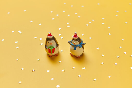 Two statuettes of penguins on yellow background
