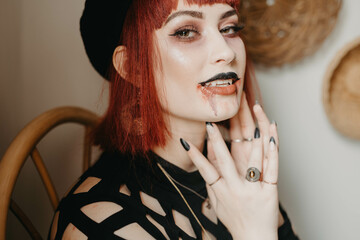 A woman getting ready for halloween and wearing vampire makeup