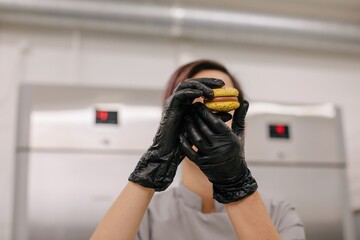 Baker with macaroon cookie in kitchen
