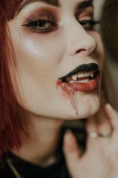 A woman getting ready for halloween and wearing vampire makeup