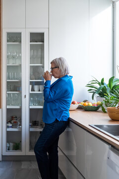 Mature woman sipping coffee in kitchen