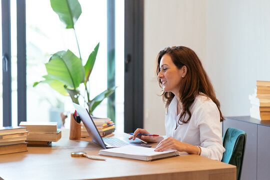 Smiling Hispanic woman working on laptop