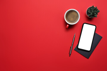 Mock up smart phone, coffee cup and notebook on red background with copy space for text.