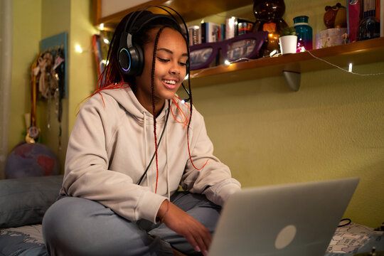 Teenage Black Gamer Sitting On The Bed At Night. 