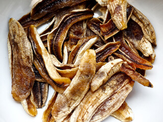 closeup home made sun dried sliced banana in white bowl, healthy fruit snack