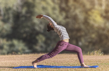 Fototapeta Young girl doing yoga on meadow park in sunny day. obraz