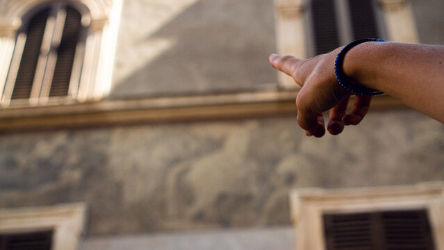 Hand pointing at a beautiful architecture house in Rome 