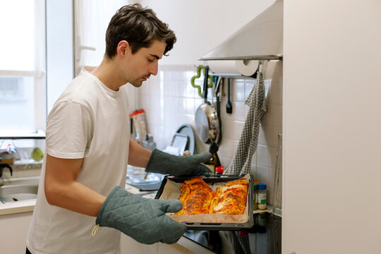 Man in kitchen takes a baked calzone out of the oven