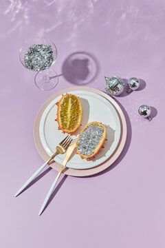 Kiwano fruit with glitter lying on plate among baubles