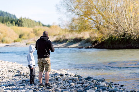 Father and son fishing by a river