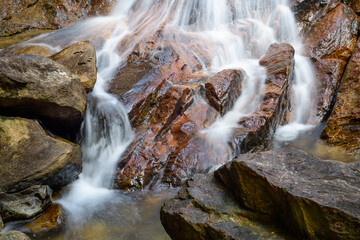 Cascade water streams splash and crash through the rocks long exposure photograph. Andahalena Ella waterfall in Beraliya rain forest.