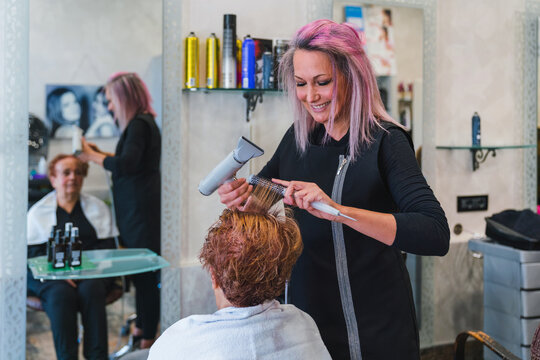 Hairdresser Combing Hair of a Senior Customer
