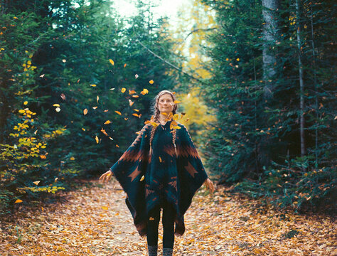 Portrait of woman in autumn throwing leaves in the air