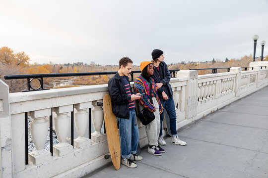 Three Teenagers Hang Out On A Bridge