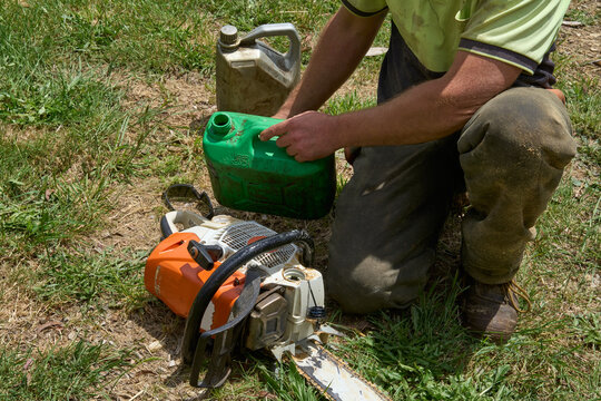 Man refuelling chainsaw - Powered by Adobe