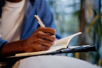 Close-up of hand writing on notebook at cafe