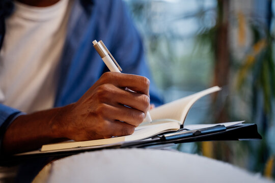 Close-up of hand writing on notebook at cafe