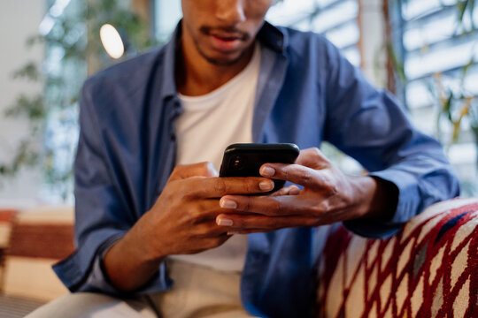 Crop image of Young man texting on phone in cafeteria