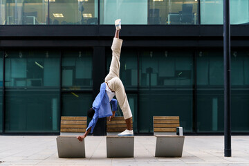 Stylish man doing yoga pose on bench
