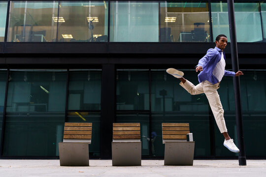 Stylish man dacing and jumping over street bench