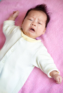 Closeup of Asian newborn baby on pink background


