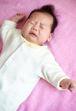 Closeup of Asian newborn baby on pink background

