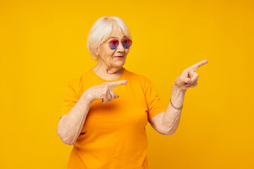 Photo of retired old lady in a yellow t-shirt posing yellow background