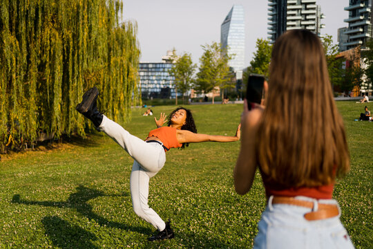 A woman filming her friend dancing in nature