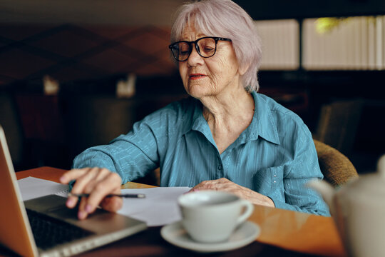 Beautiful mature senior woman working in front of laptop monitor sitting Retired woman chatting unaltered