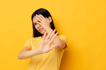 Charming young Asian woman in a yellow t-shirt holding his head discontent studio model unaltered