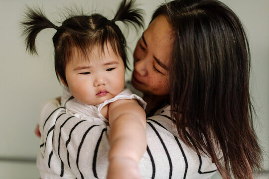 Loving Asian mom with holding beautiful baby