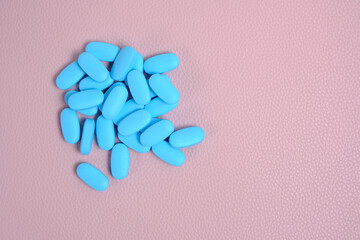 Blue pills, vitamins on a pink background.