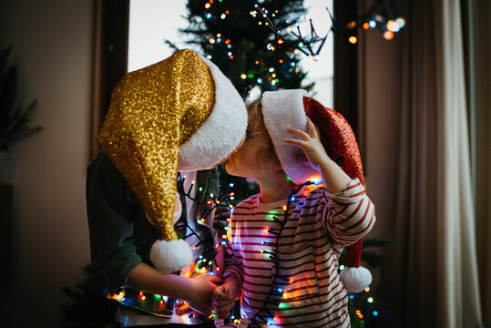 Two kids kissing in front of the Christmas tree