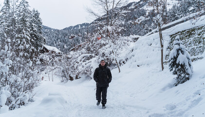 man takes a walk in the snow with the mountains in the background