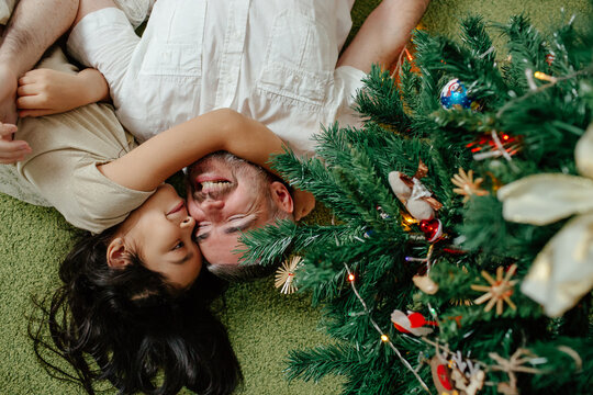 Father and daughter lying under Christmas tree