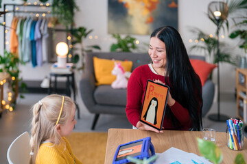 Cheerful woman and girl studying together