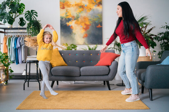 Diverse nanny and girl dancing together