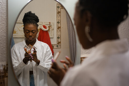Black Girl Making Up In Front Of The Mirror At Home.
