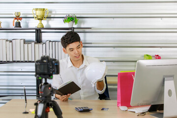 Fototapeta premium Adult asian seller man look intend holding looking at camera to present product via live online for shopping online with e-commerce sell.