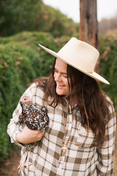 Woman Wearing Flannel Holding Chicken and Smiling