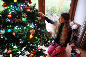 A girl decorating a christmas tree on a chilly day