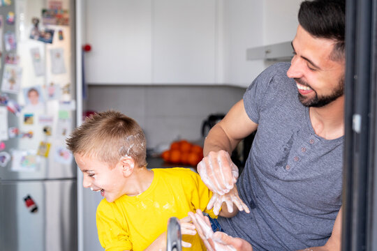 dad and son having a foam war with each other's hands