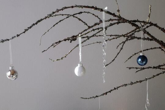 Glass Christmas toys hanging on dry branch