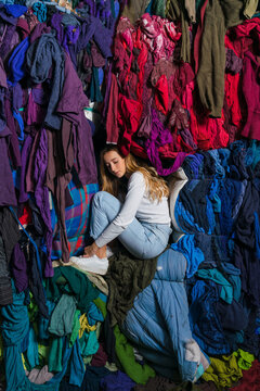 Young Woman Surrounded by Used Clothes